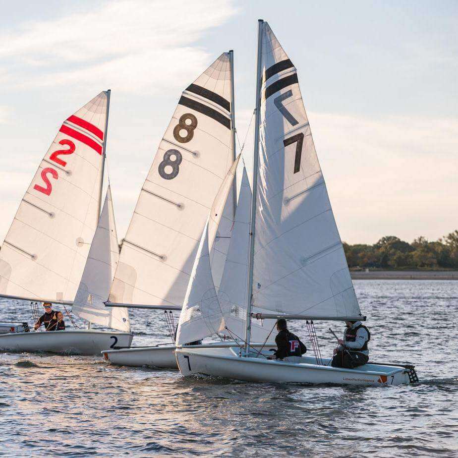 Students ride a sailboat on sunny water.