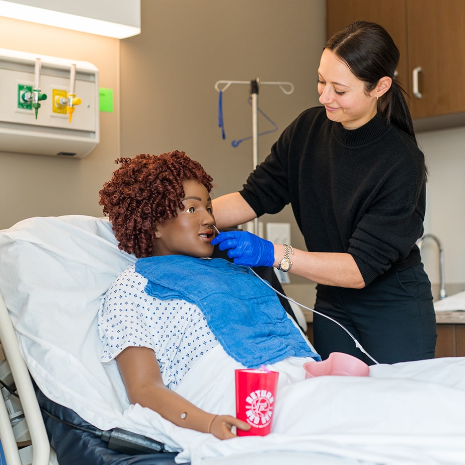 Fairfield nursing student tending to a simulation doll 'patient' during a lab simulation.