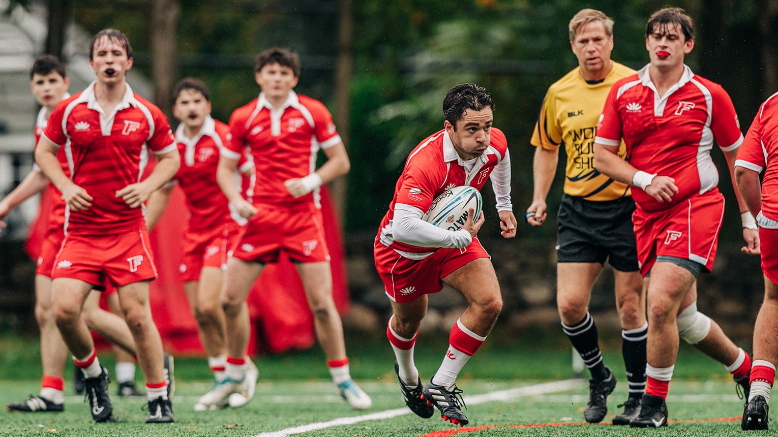 Men in red uniforms actively participating in a rugby game, demonstrating skill and camaraderie during play.