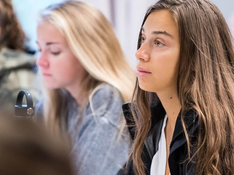 A classroom scene featuring a group of girls seated at desks, participating in a collaborative learning environment.