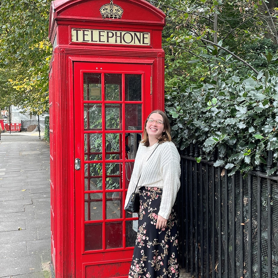 Fairfield student posing excitedly with an old, red telephone booth in the UK.