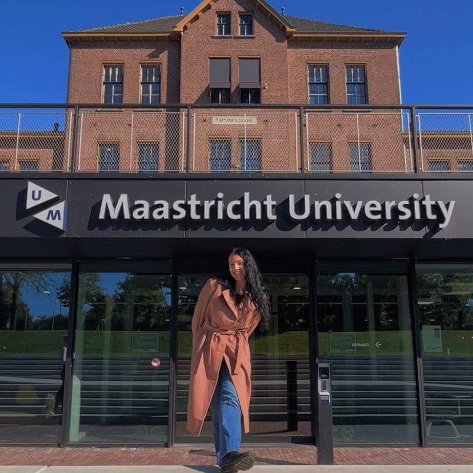 Fairfield student posing excitedly outside the Maastricht University (Netherlands) entrance.