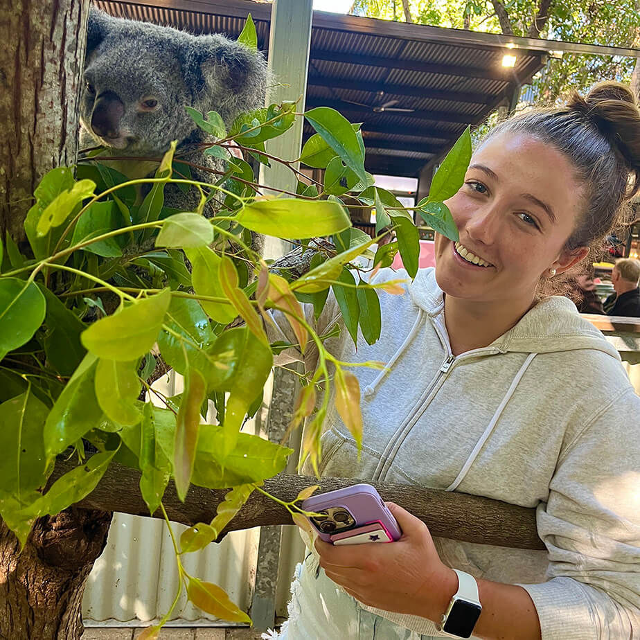 Fairfield student posing excitedly with a native Australian koala, perching on a tree.