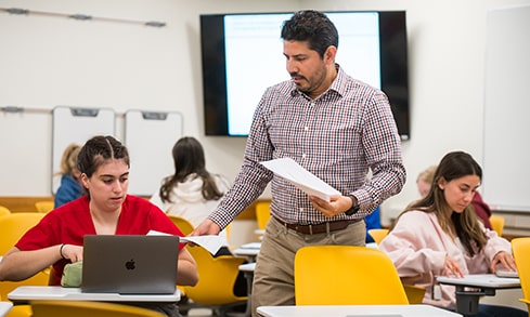 Professor handing back an essay paper to a student in class.