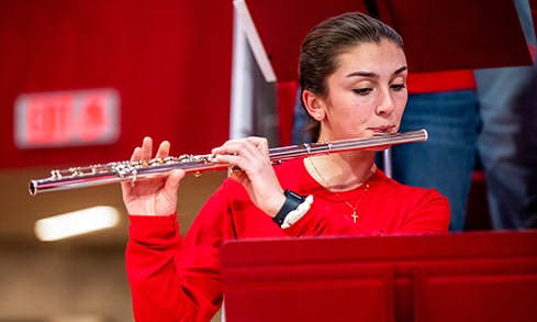 Pep band student playing the flute at an on-campus game.