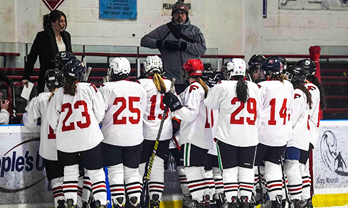 Women's Ice Hockey team on ice posing for group photo.