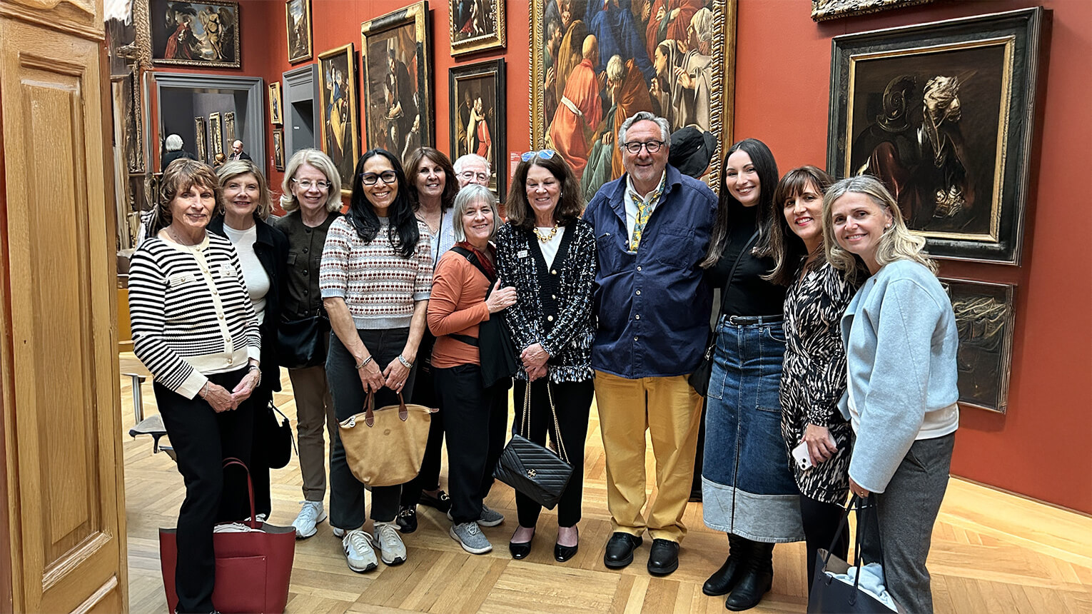 A cheerful group of people stands together, posing for a photograph in a museum environment.