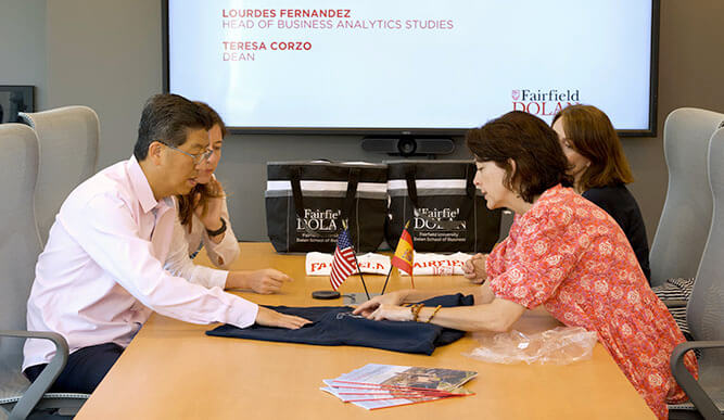 A man and a woman among a group of people sitting at a table, sharing ideas and enjoying each other's company.