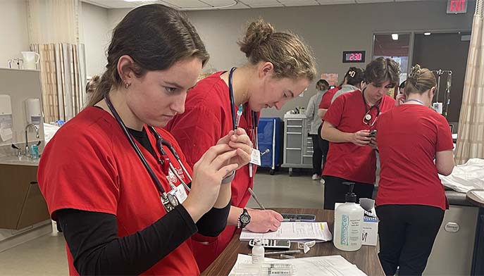Image of a group of nursing students engaged in hands-on training at a hospital, learning patient care techniques.