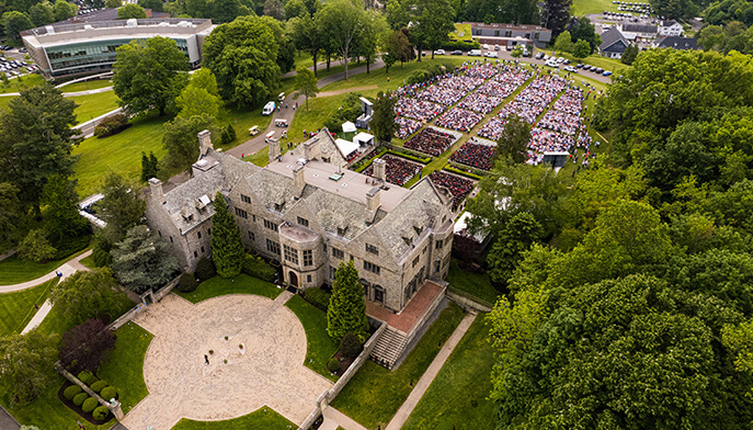 Aerial perspective of Bellarmine Hall enveloped by dense trees, highlighting its impressive architecture and serene setting.