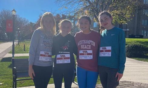 Four students standing next to each other wearing race bibs.