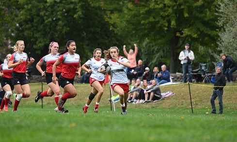 Women's Rugby club team playing match on field.