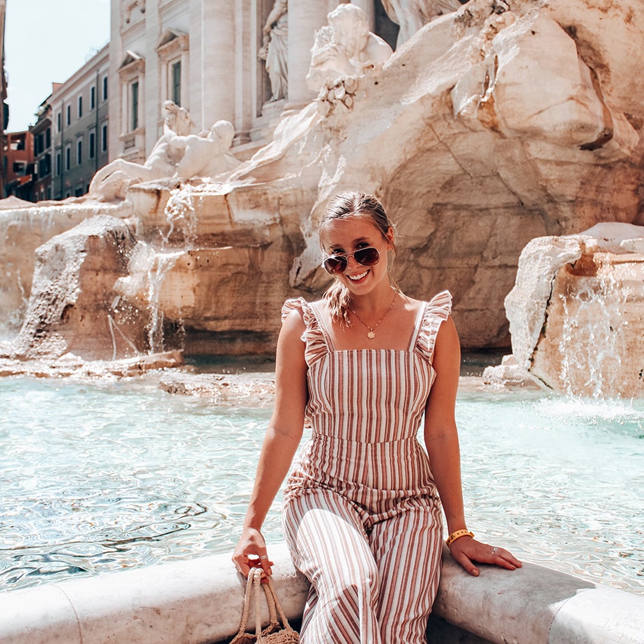 Fairfield student sitting and smiling on the ledge of the Trevi Fountain in Rome, Italy.