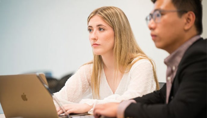 Two graduate business students pay attention during a business class.