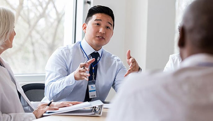 A healthcare administrator speaks with physicians about hospital policy.