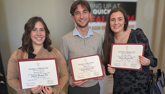 Three students proudly displaying their Alpha Sigma Nu (ASN, National Jesuit Honor Society) membership certificates.